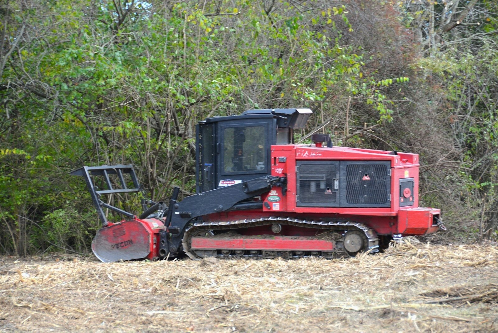 Forestry mulcher clearing dense brush at a field edge
